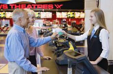 Couple Paying at Ticket Counter in Movie Theater