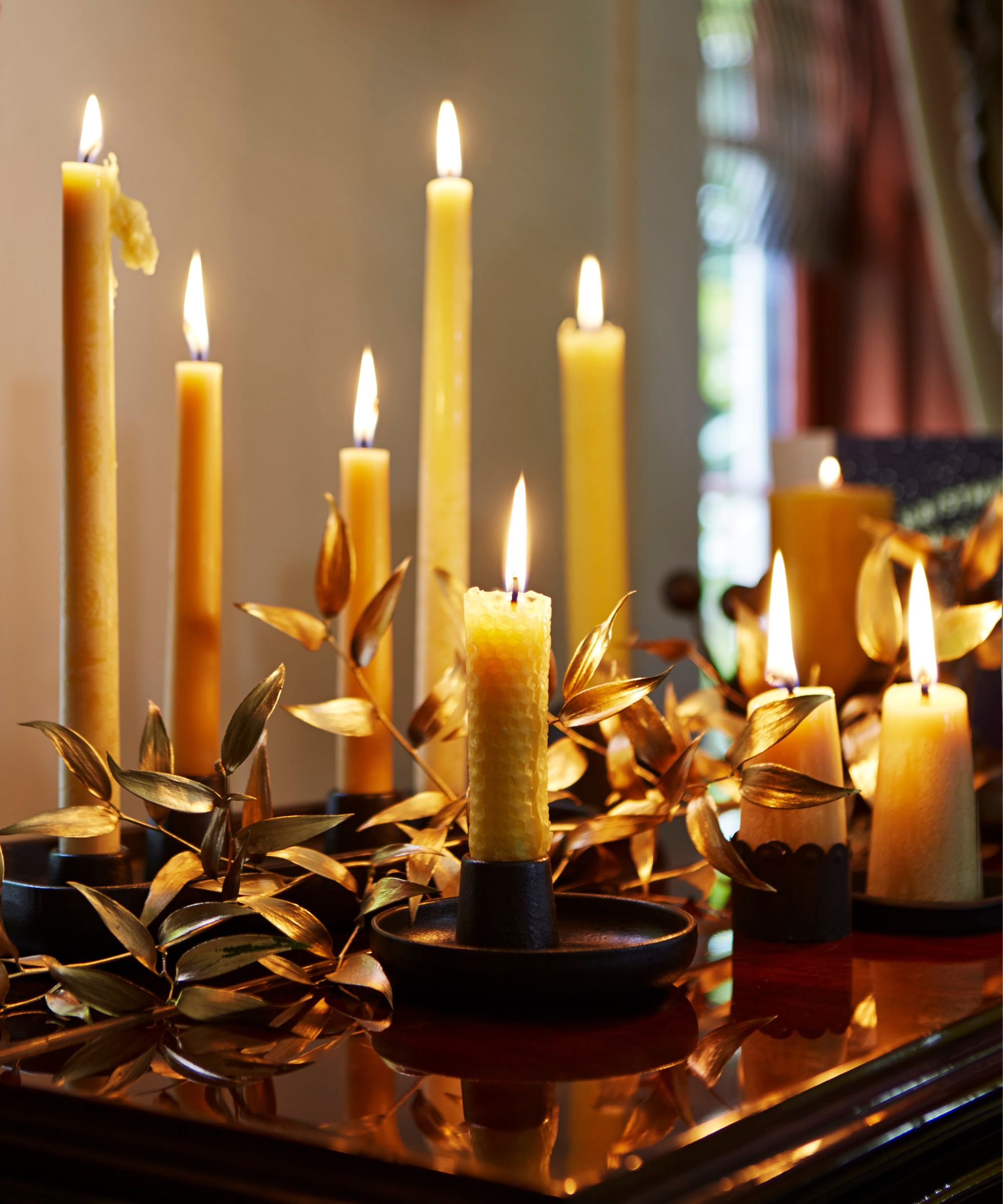 White future candles arranged around a gold metal leaf garland