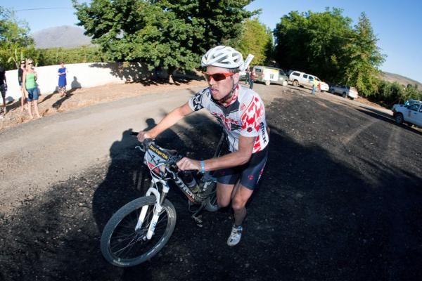 Lucus Fluckiger pushes his bike with a broken derallier into waterpoint one