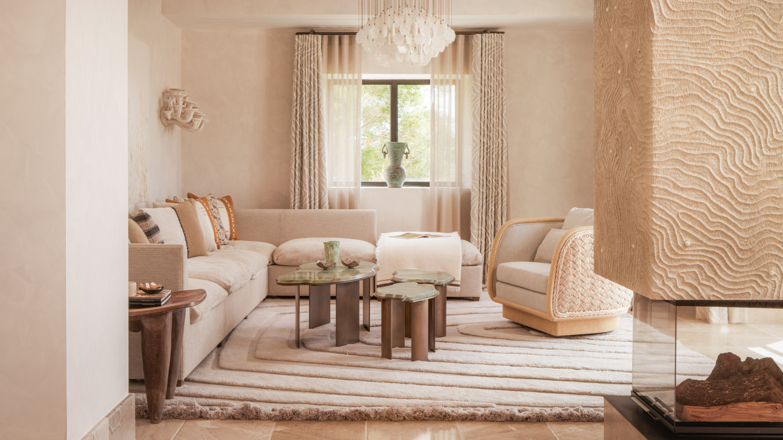 Cream living room with textured central fireplace, cream corner sofa, green armchair and wood and green marble coffee table