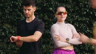 A photo of an athletic man and woman back-to-back, wearing the Suunto Run running watch.