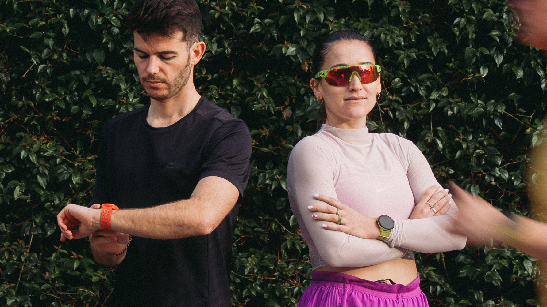 A photo of an athletic man and woman back-to-back, wearing the Suunto Run running watch.