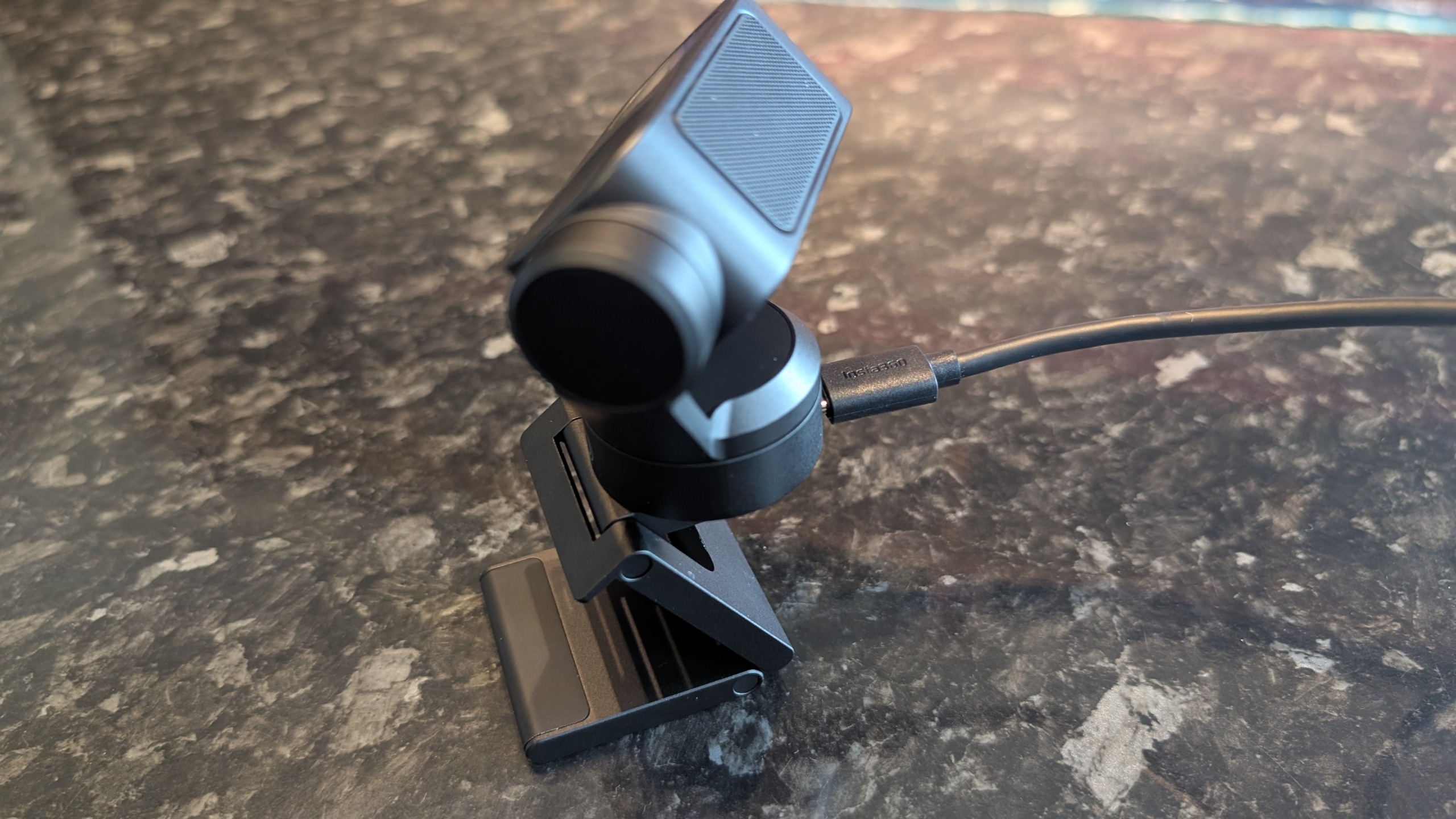 The Insta360 Link 2 Pro webcam, pictured on a marble worktop.