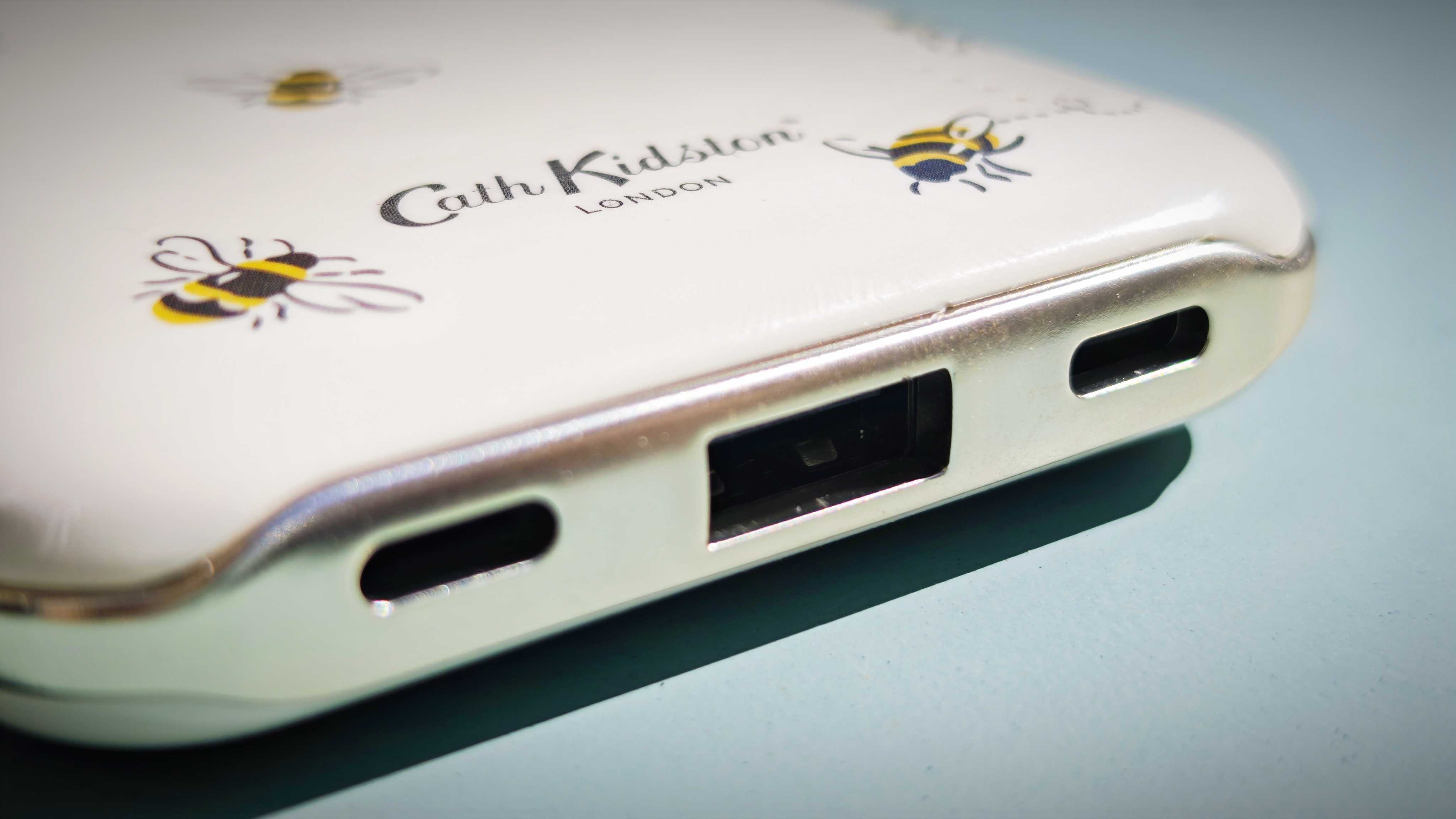 A Cath Kidston branded power bank with bee patterns on a blue-green table