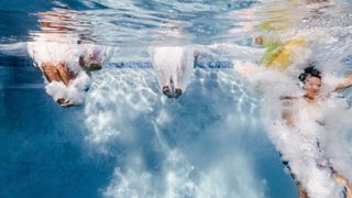 Three women jumping into swimming pool