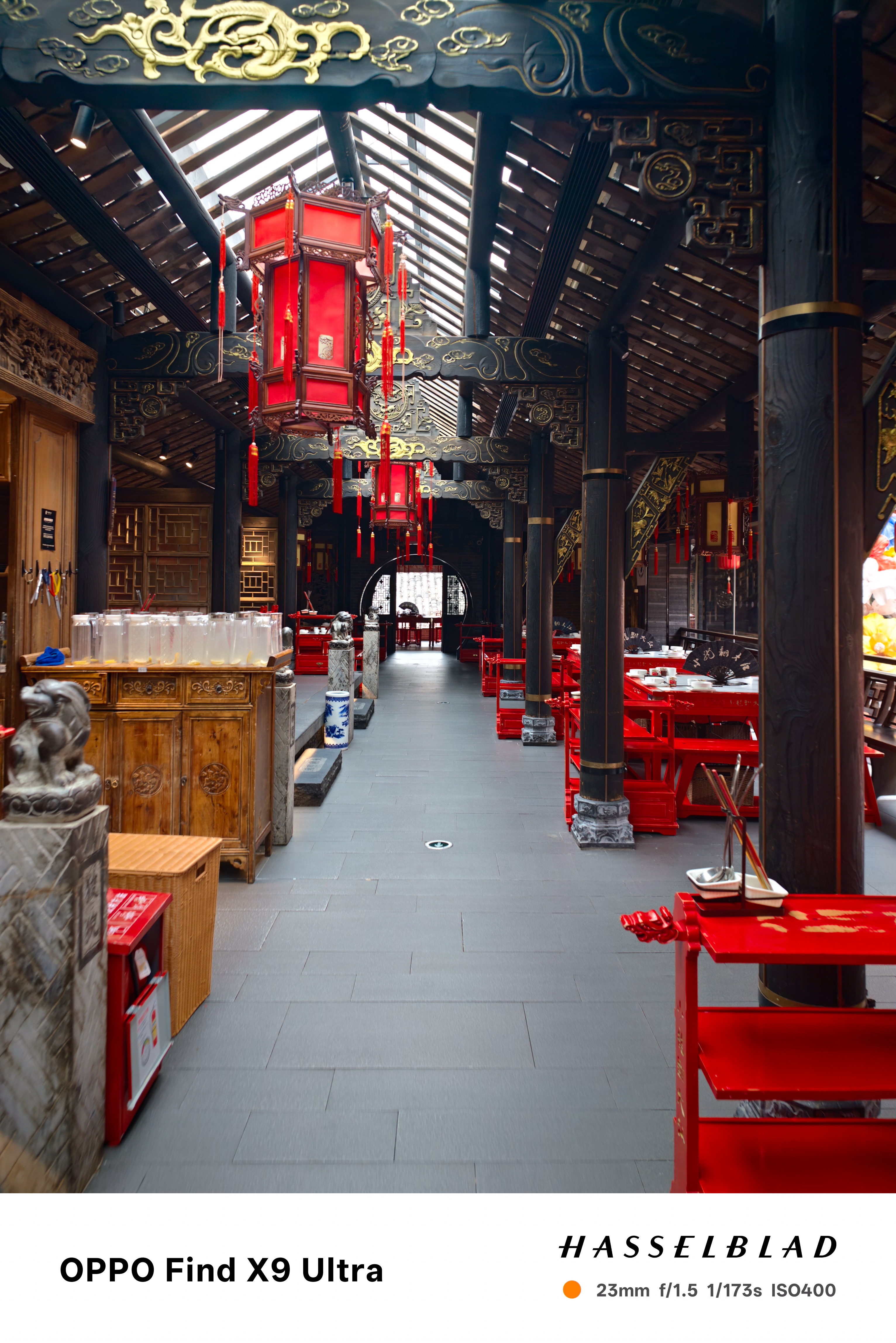 Traditional restaurant interior with red lanterns, dark wood beams, and red tables
