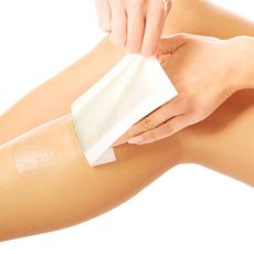 Close-Up Of Woman Waxing On Leg Over White Background - stock photo