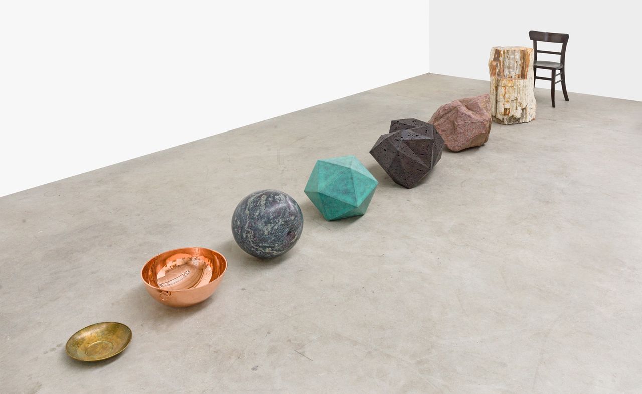 Alicja Kwade, Transformer, 2021 bronze bowl, copper bowl, Amadeus granite sphere, Ostsee Earl patina, milled lava rock, milled granite, petrified wood, bronze chair.