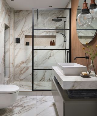 shower with floor to ceiling screen in bathroom with marble tiling
