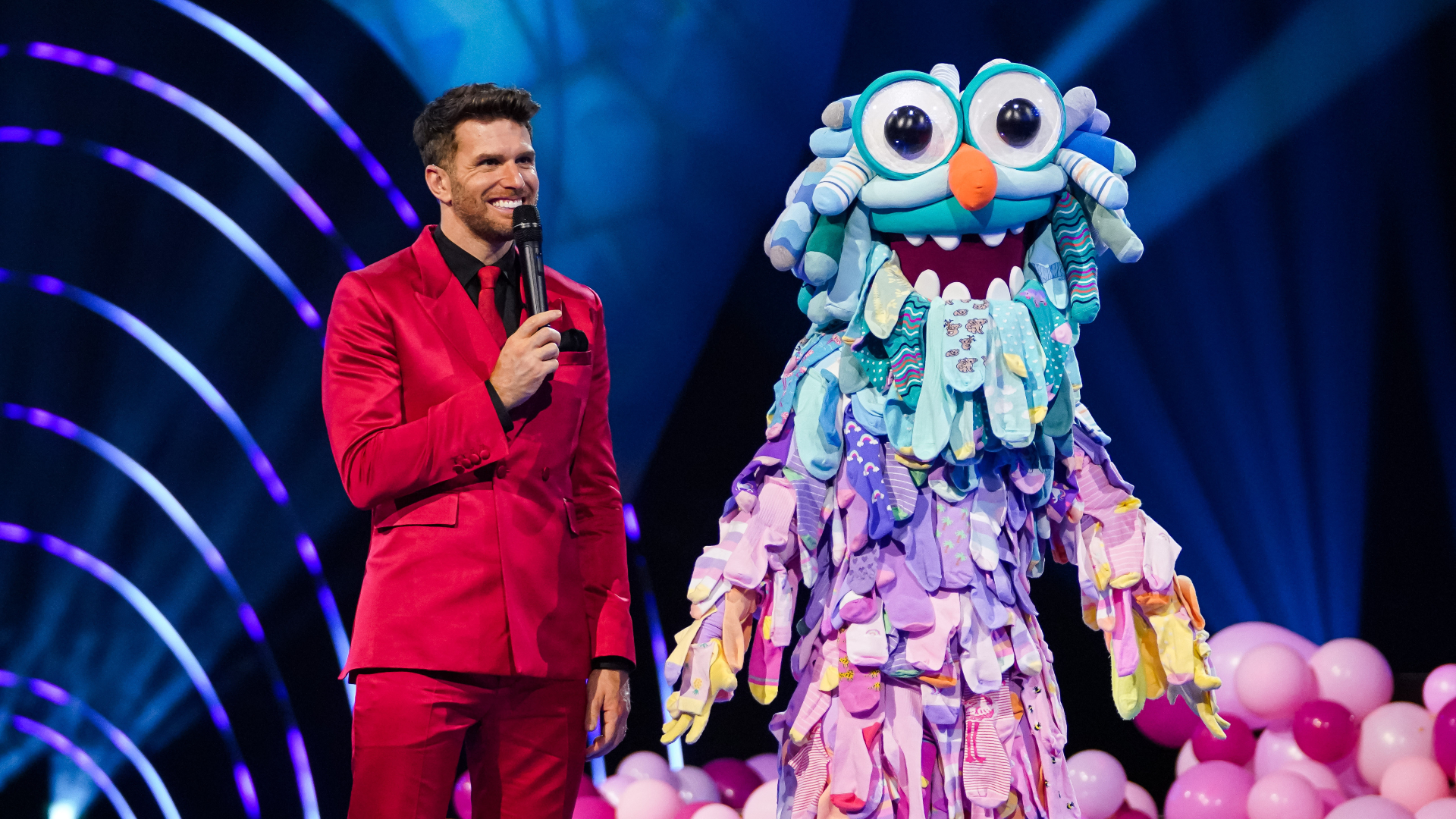 Joel Dommett stands next to Odd Socks in The Masked Dancer UK 2022