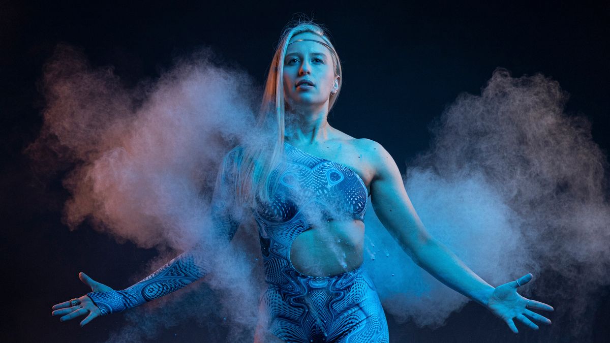 A portrait of a female wrestler in a blue outfit looking at the camera