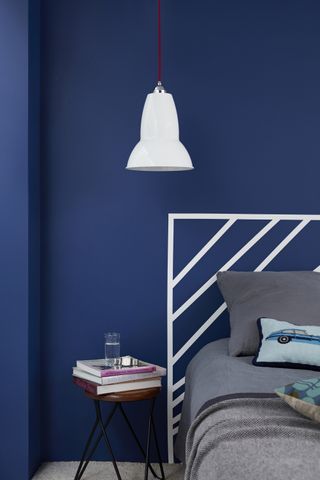White painted DIY headboard on a dark blue wall. Wall painted in Sapphire Salute and background/headboard in White Mist, both Dulux