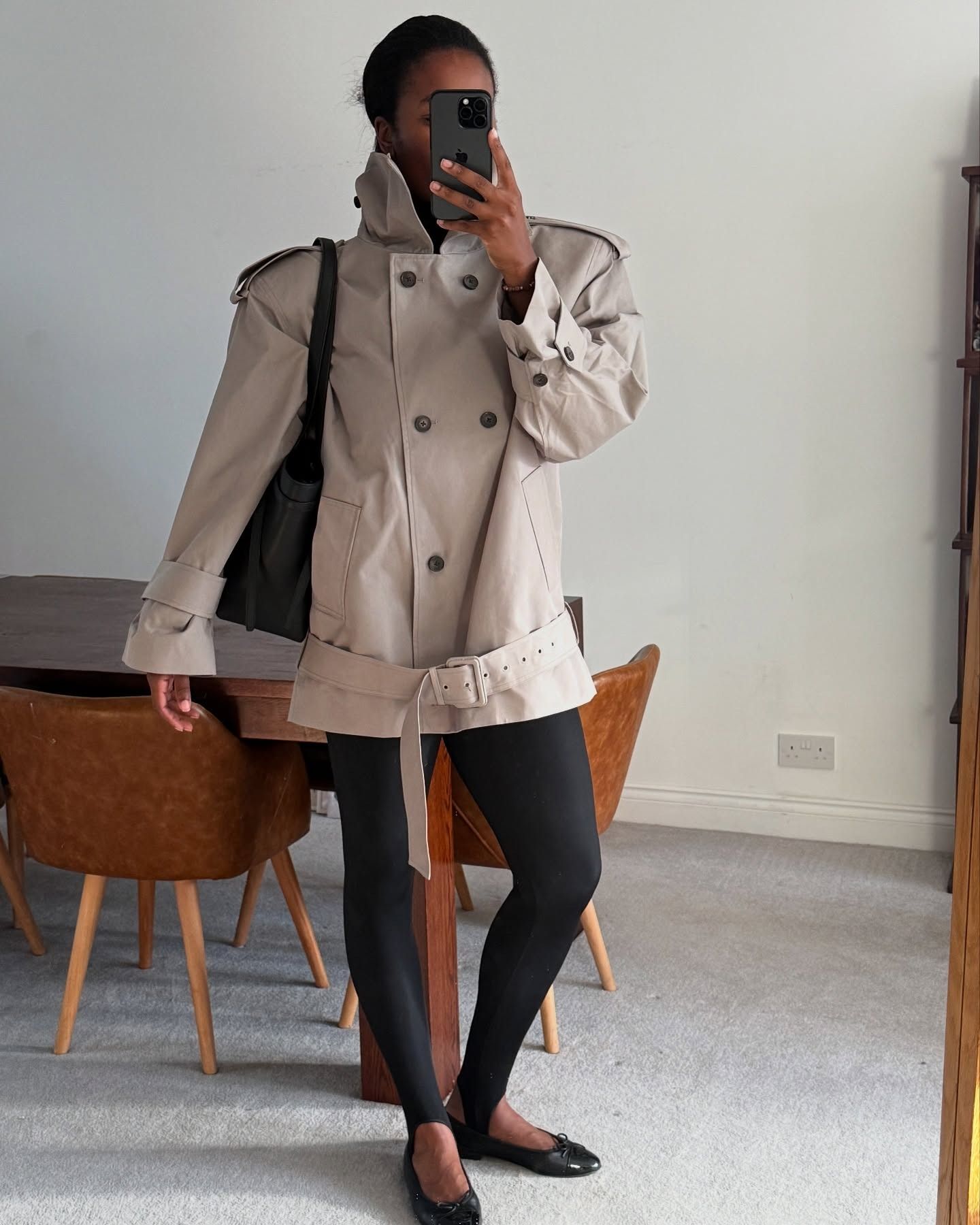 Influencer Marilyn NK in a high-neck trench, stir-up leggings, black ballet flats, and a oversized tote.