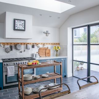 blue and white kitchen with wooden peg rail, slate floor tiles and crittal french doors to garden