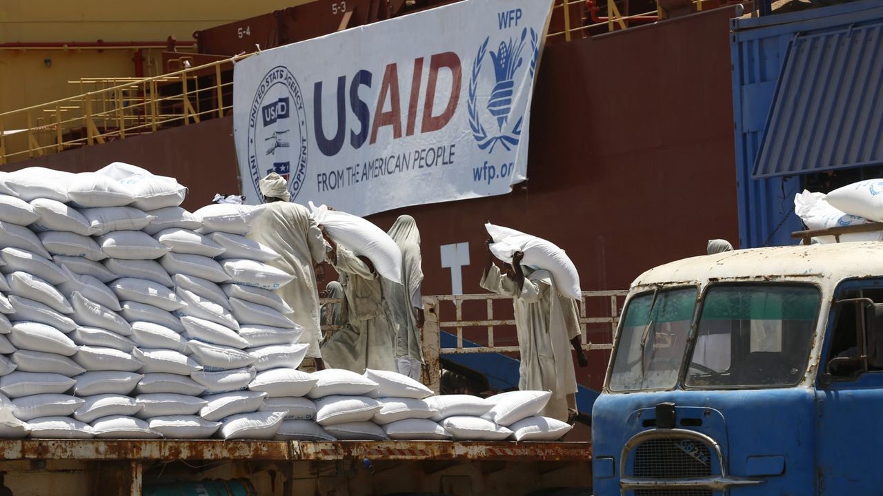 Workers in Sudan unload bags of cereal from USAID in 2018