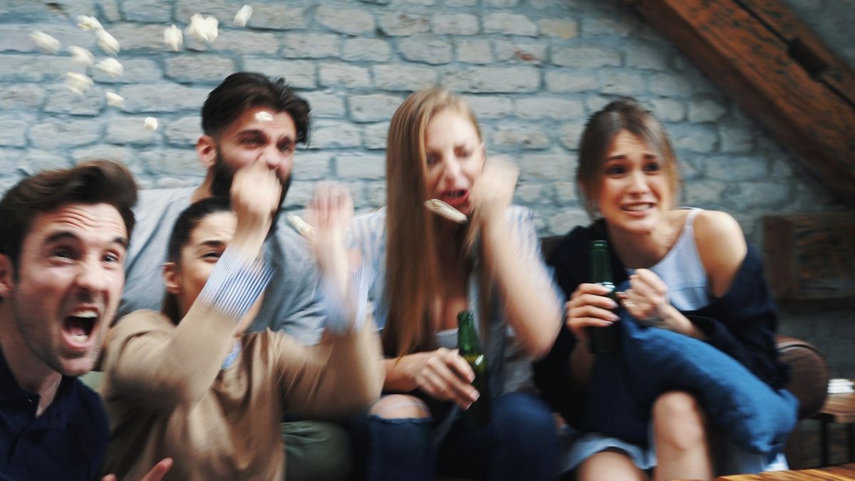 Group sitting on sofa responding to sport on TV