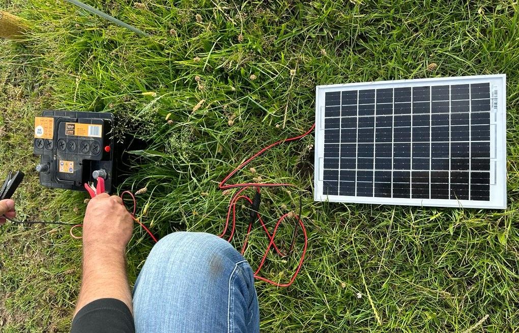 A solar panel charger being attached to a car battery