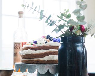 Homemade cake on a stand next to vase of flowers