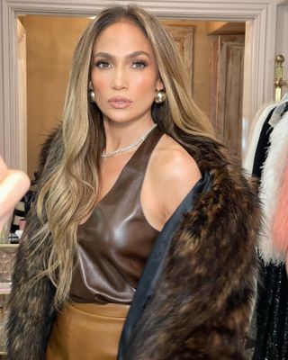 Jennifer Lopez wearing shades of brown with a fur coat and gold bubble earrings