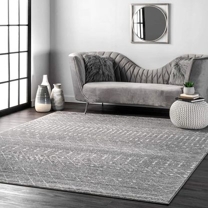 white wall with mirror and grey sofa with cushions and grey carpet