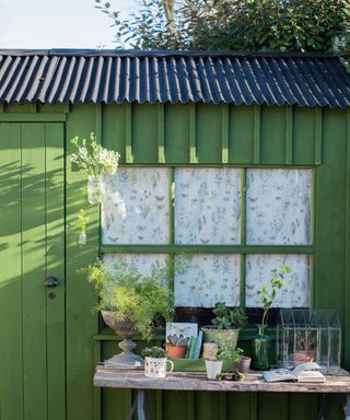 green shed with windows in garden with table