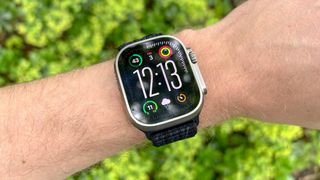 Apple Watch Ultra 2 on a person's wrist in front of a bush outside