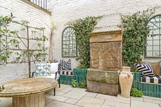 Courtyard garden with white walls, mirrors, espaliered fruit trees and reclaimed stone features
