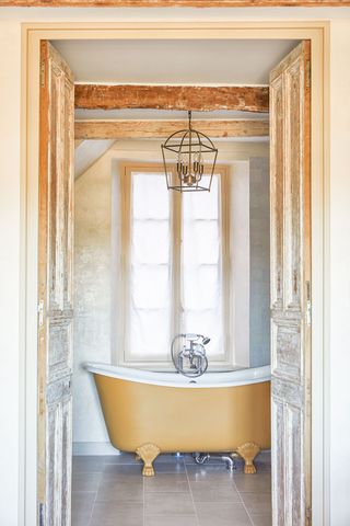 Bathroom with yellow roll top bath in 16th century French townhouse in Saint-Paul de Vence