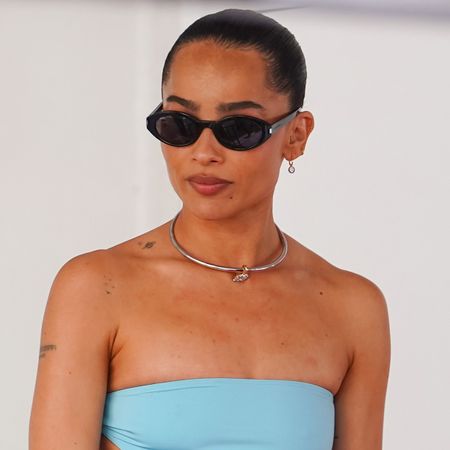 Zoe Kravitz seen attending the Lenny Kravitz Hollywood Walk of Fame Star Ceremony on March 12, 2024 in Los Angeles, California wearing a turquoise strapless top, silver collar necklace, and black sunglasses.