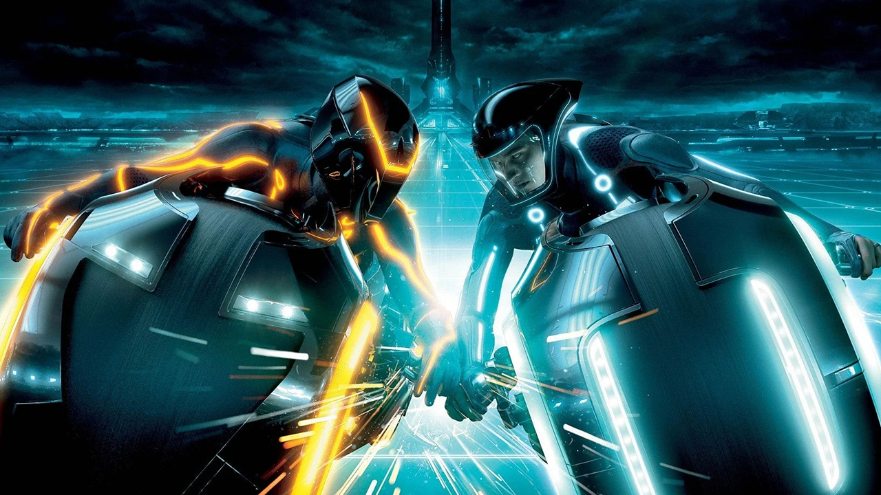 Screenshot from the movie Tron: Legacy. Two people speeding head-to-head on Light Cycles (futuristic motorcycles). The person on the left is wearing a black bodysuit and helmet, both with orange light trim. The person on the right is wearing a black bodysuit and helmet, both with blue light trim.