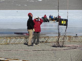 Scientists watch as an airborne electromagnetic mapping sensor lifts off the ground near Lake Fryxell in the McMurdo Dry Valleys, Antarctica.