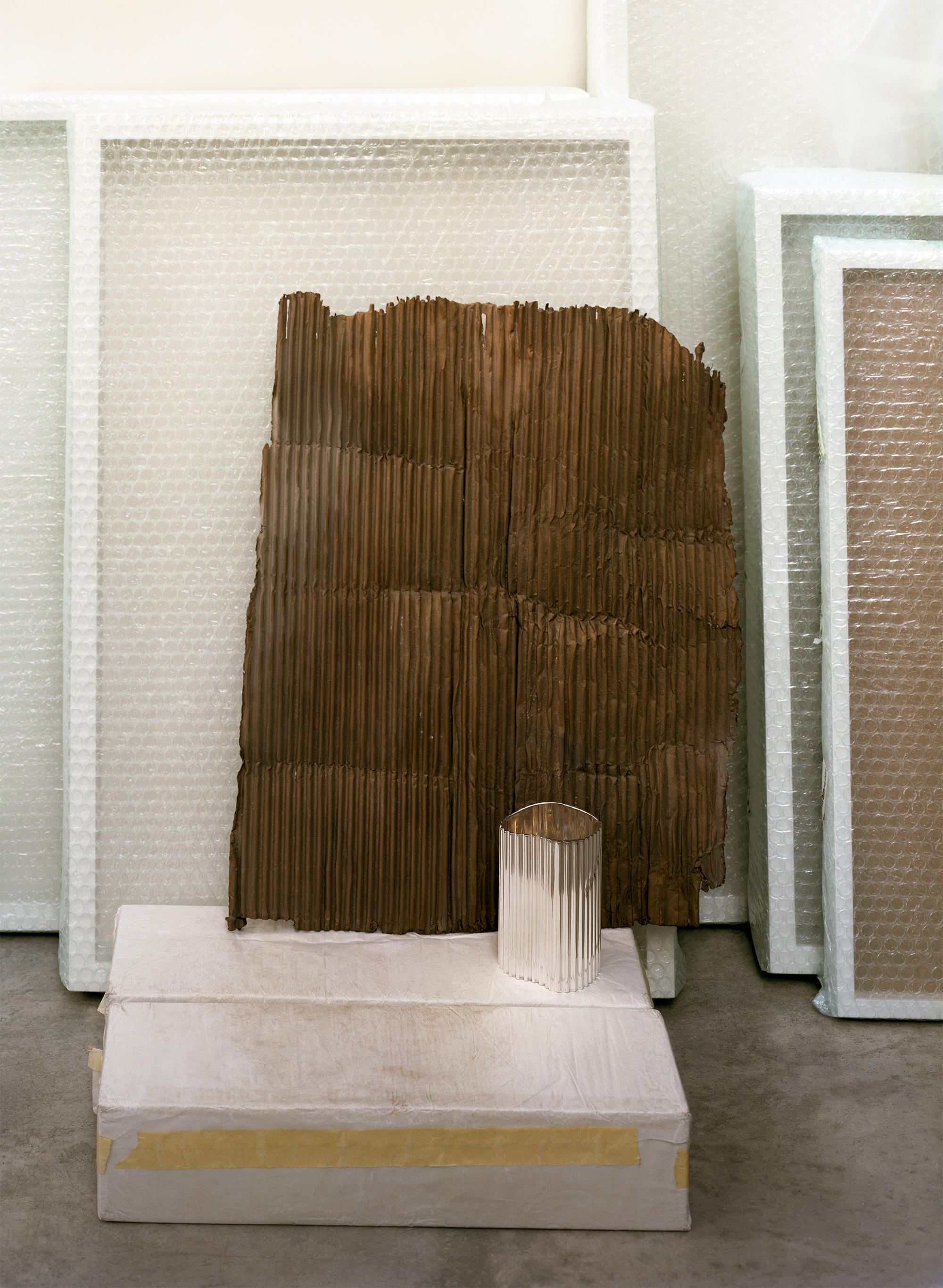 Silver objects with a ridged surface, shown in the context of a messy artist&#039;s studio