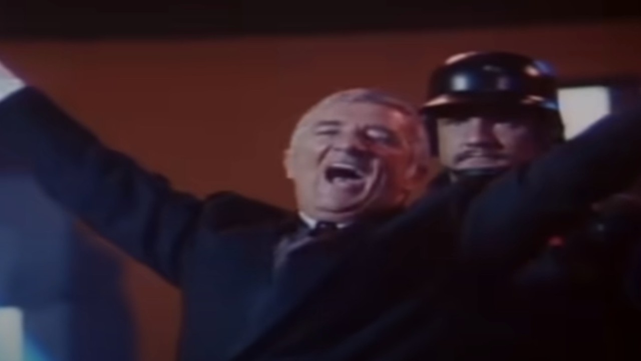 Richard Dawson throwing out his arms in The Running Man