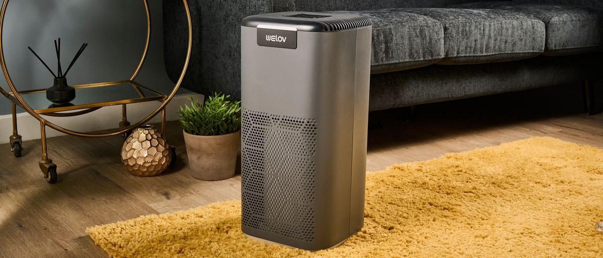 The AiDot Welove P200 Pro air purifier is pictured on top of a mustard rug in a living room.