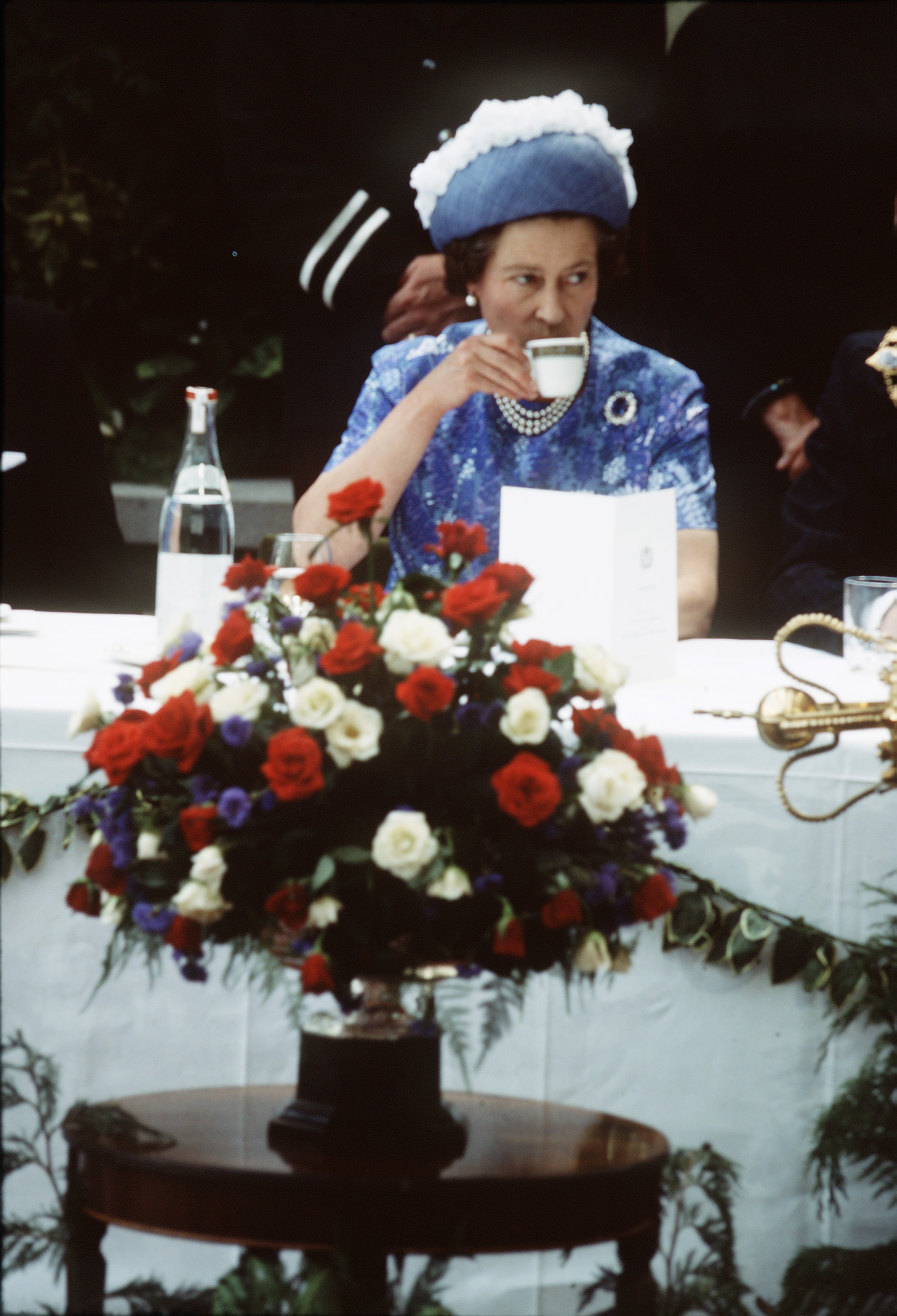Queen Elizabeth drinking tea at a table