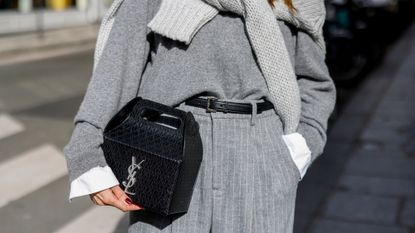Woman wearing a grey jumper, carrying a YSL take-away box bag