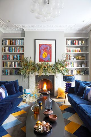 Christmas living room with decorated mantel piece and blue velvet sofas