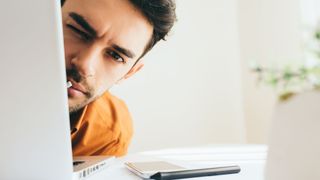 Man hiding behind an open laptop