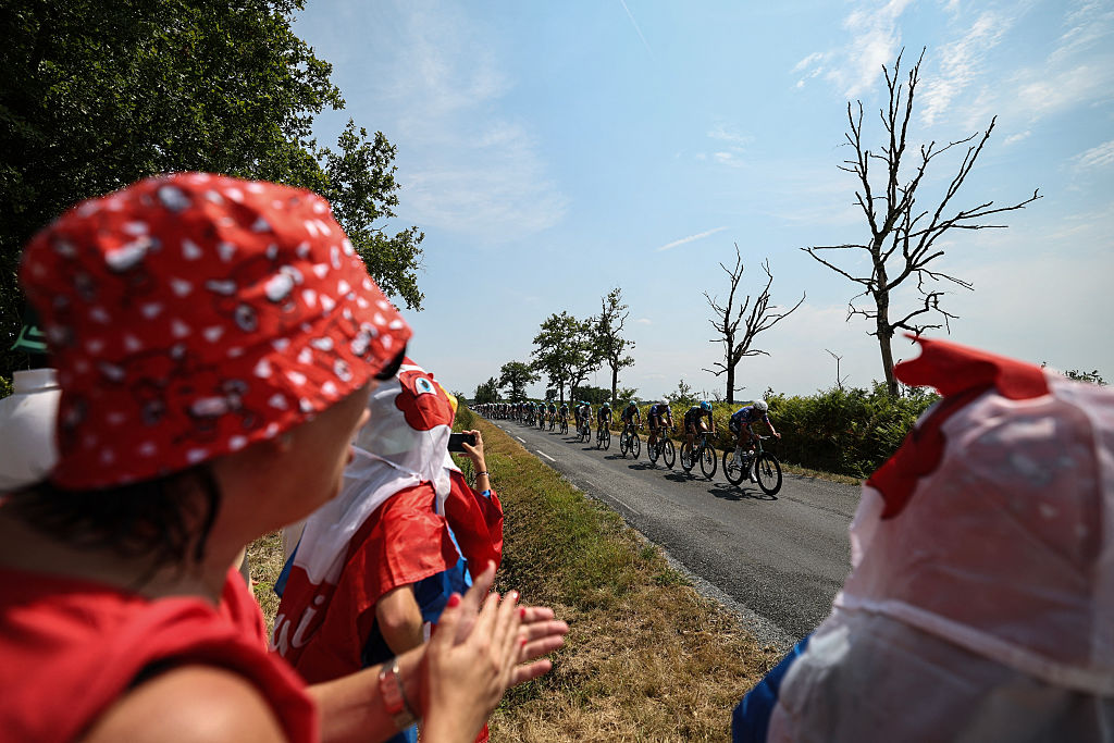 Spectators cheer along the race route as the peloton chases the breakaway on the 7th stage