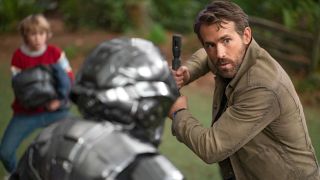 Ryan Reynolds defends himself with a staff while Walker Scobell watches in The Adam Project.