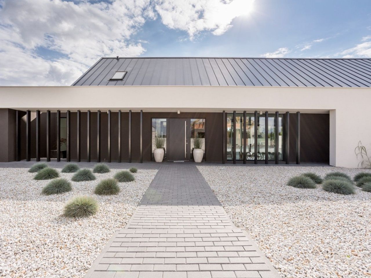 A gravel lawn and a stone path in front of a modern looking house