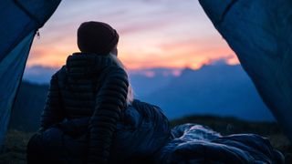 how to stay warm in a tent: camper watching sunrise