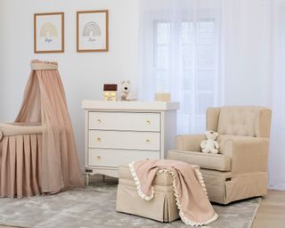 pink nursery with armchair, foot rest, chest of drawers and cot