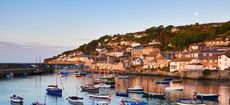 The first light of dawn catching the cottages along the waterfront, overlooking the picturesque Cornish harbour of Mousehole.