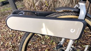 a black city bike is photographed with the CLIP e-bike conversion kit attached to the front wheel