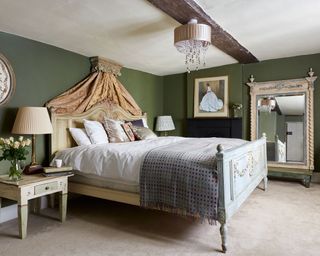 green farmhouse bedroom with antique bed and large antique mirror