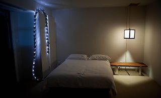 A bedroom with light and Schindler Lantern.