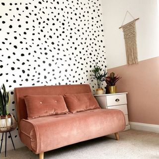 Spot Wall Sticker wallpaper with a peach colored sofa and a white drawer topped with plants next to a two-colored wall decorated with a macramé wall hanging