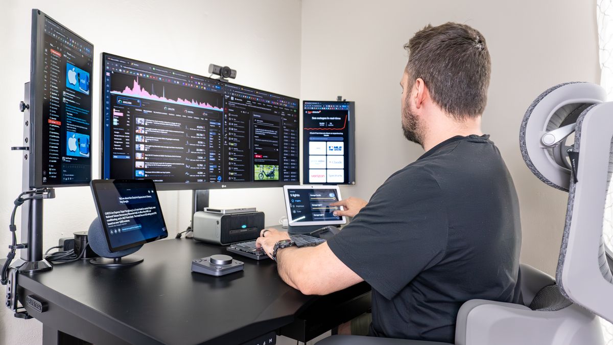 A person working at a desk with a triple monitor setup with a smart display on either side