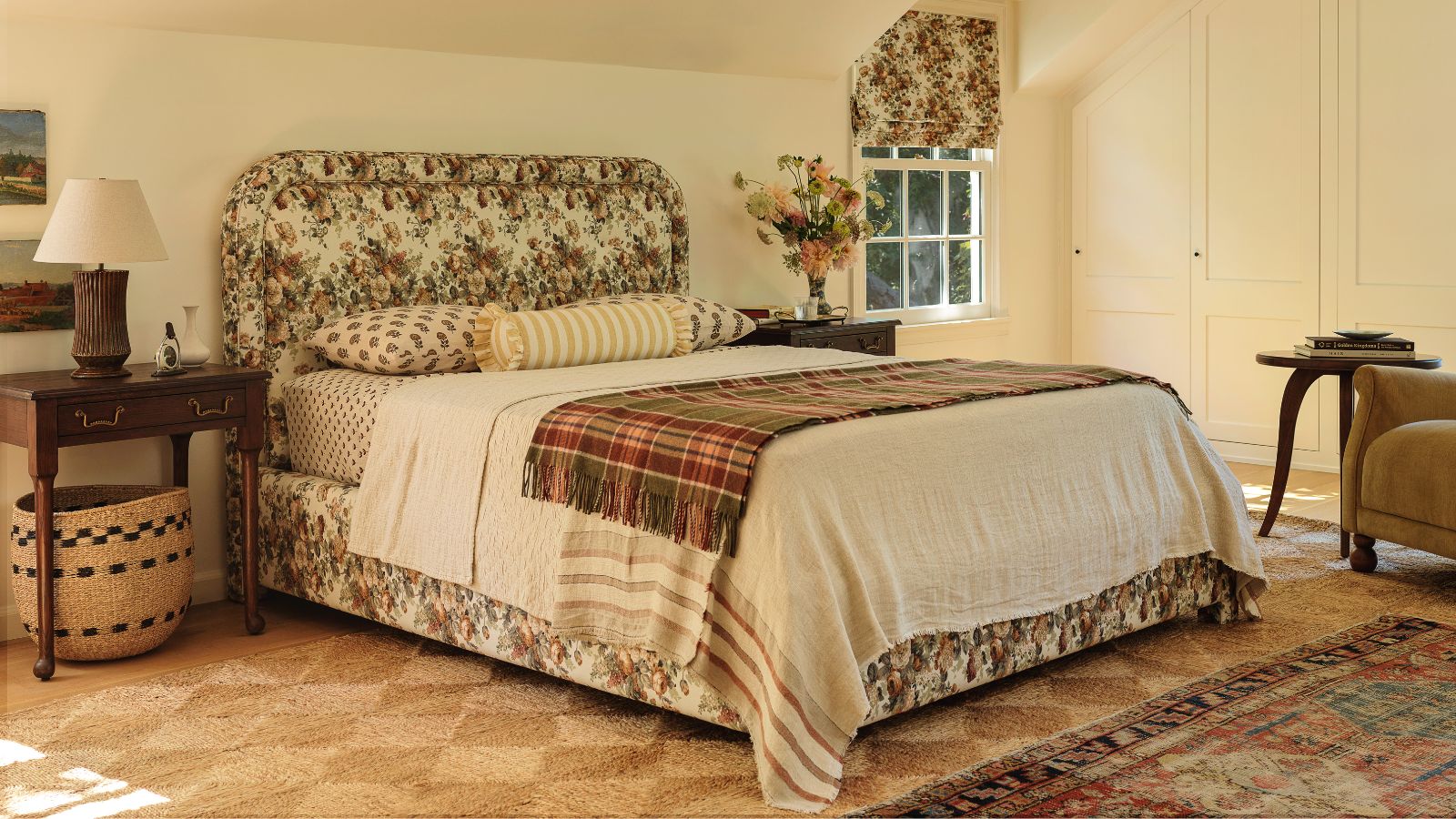 vintage style bedroom designed by heidi caillier for her collaboration with lulu and georgia using a natural woven rug, floral upholstered bed, and a velvet arm chair